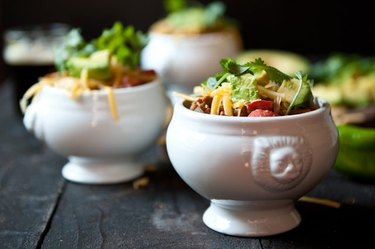 Fresh batches of chili served in porcelain dishes, topped with colorful garnishes.