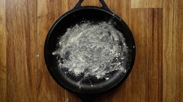 Covering a cast iron skillet with coconut flour.