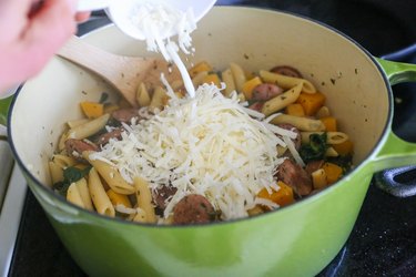 Adding cheese to a pot of pasta
