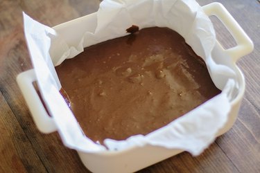 Brownie batter in a baking dish lined with parchment.