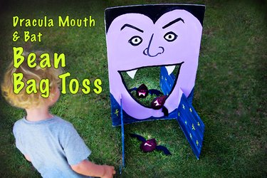 A purple face painted onto foam core with a hollow mouth and bat-shaped bean bags