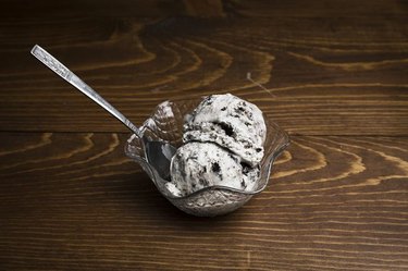 A small glass bowl of cookies and cream ice cream on a wooden table