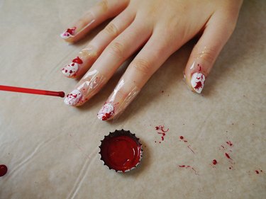 A cocktail straw splattering red polish over the white nails.