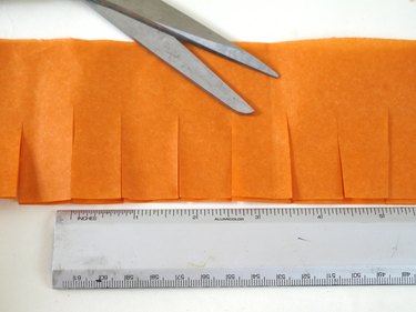 A strip of fringe with a ruler and scissors.