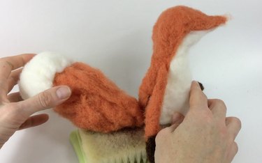Female hands holding a felted fox tail and body