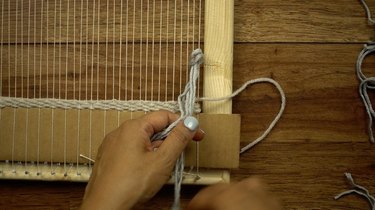 Adding fringe knots to woven wall hanging.