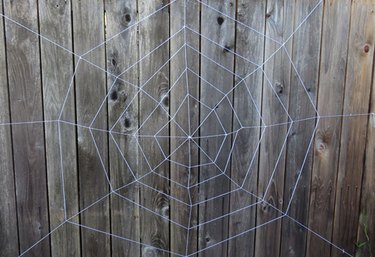 Large spider web hanging on a fence outdoors