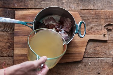 Adding broth to pot with chicken