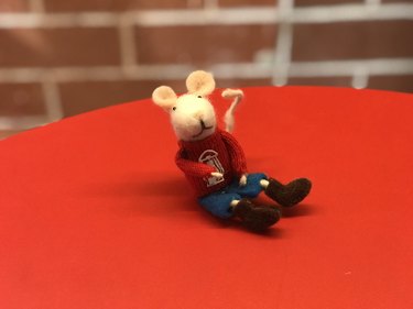 Small felt mouse resting on red tablecloth