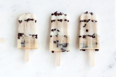 Three chocolate chip ice pops with alternating layers on marble