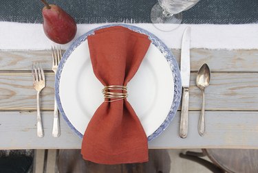 Gold wire napkin rings being used with rust-colored napkins on a fall table.