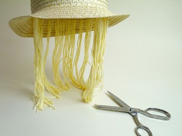 The hat with the trimmed yarn and a pair of scissors.