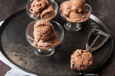 Three bowls of ice cream on a silver tray with an ice cream scoop