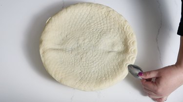 Pressing spoon into edge of dough to create scalloped pattern