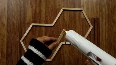 Gluing popsicle sticks for DIY hexagon shelves.