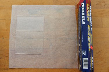 A sheet of wax paper with a clear acrylic picture frame laying directly on the wax paper