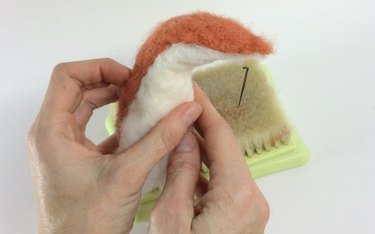 Female hands holding a white and orange felted fox body