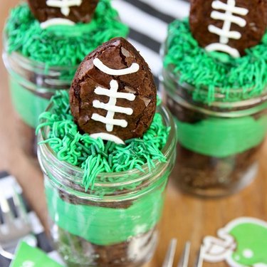 Moist football brownies inside a turf-themed mason jar filled with green buttercream.