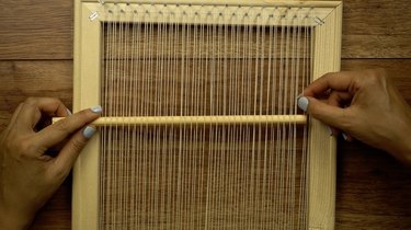 Using a round dowel as a shed stick for weaving on DIY simple frame loom.