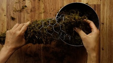 Packing a chicken wire cone form with moist sphagnum moss.