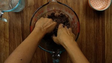 Mixing ingredients for gluten-free no-bake chocolate almond crust by hand.