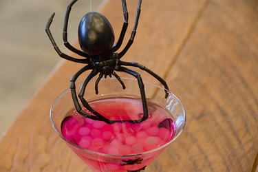Martini glass filled with a raspberry lemon drop and boba as spider eggs