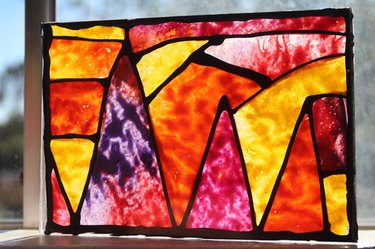 The completed, pieced version of the melted crayon stained glass, backlit by a sunny window