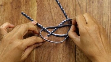 Tying a knot to make a knotted bracelet from a zipper.