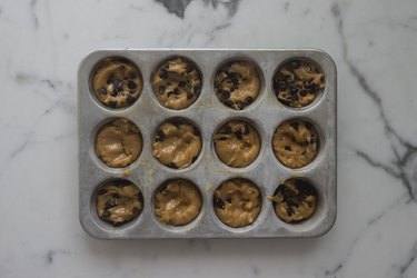 Divide the cookie dough between the cupcake pans.