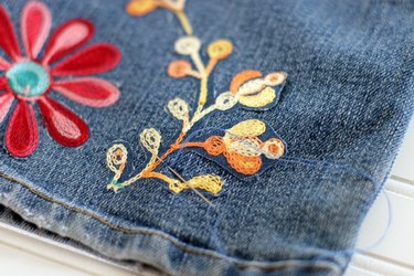 Tack embroidery pieces with a needle and thread