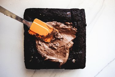 Generously spread the frosting all over the brownie top.