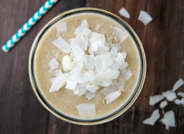 A bird's eye view of a coconut cream pie smoothie sprinkled with coconut flakes.