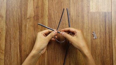 Tying a knot to make a knotted bracelet from a zipper.