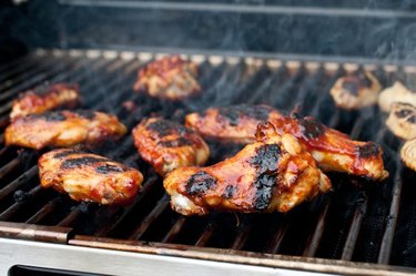 Charred chicken wings atop a steaming hot grill.