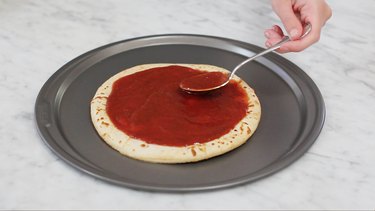Spreading pizza sauce on crust