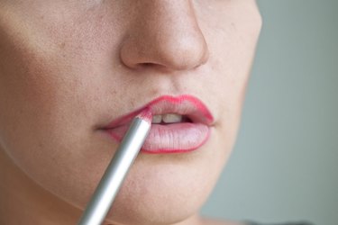 a woman applying red lip liner