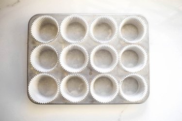 A muffin tray lined with paper liners.