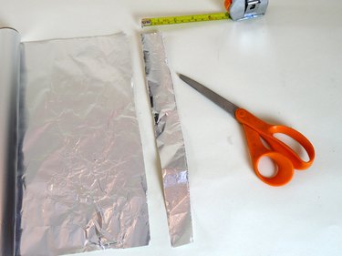 Scissors and a roll of aluminum foil with a 1-inch strip cut off.