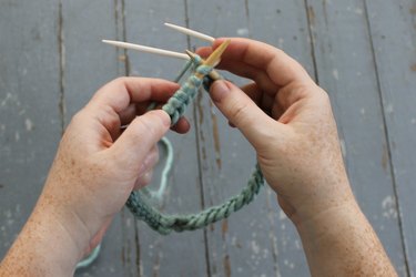 Holding the cable needle in the back as you knit