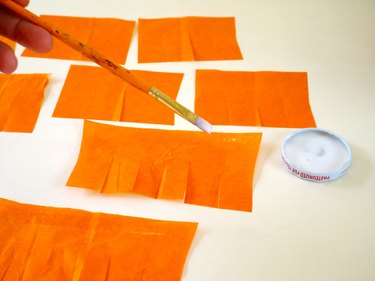 The smaller strips of fringe with a paintbrush applying glue.