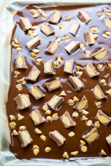 Pour melted chocolate onto sheet pan and sprinkle with peanut butter chips and peanut butter cups.
