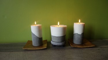 Modern DIY candles with cement base lit on table.