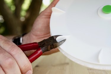 Side snips are shown cutting the fins off a salad spinner top