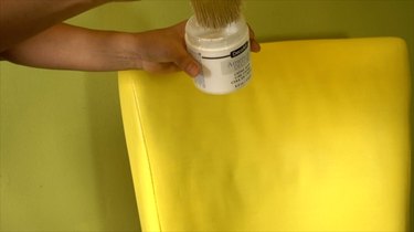 Applying cream wax to fabric upholstery painted with chalk paint.