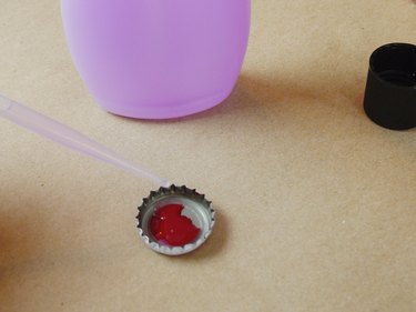 Bottle cap with red polish and an eyedropper dropping remover into the polish to thin.