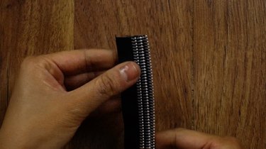 Gluing three zipper pieces of equal lengths to create a braided zipper bracelet.