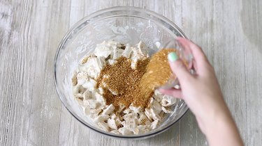 pouring gold sugar onto chocolate-coated chex cereal