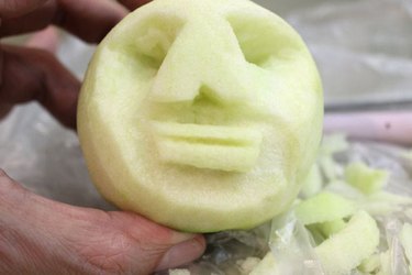 Carve eyes and a mouth in the peeled apple