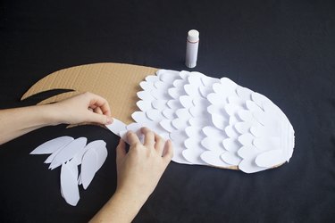 Adding paper feathers to the diy cardboard wings.