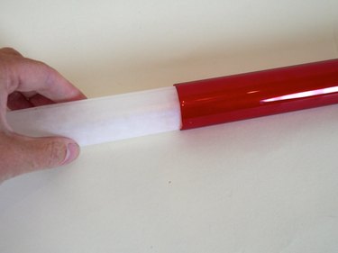Wax paper being inserted into a red tube.